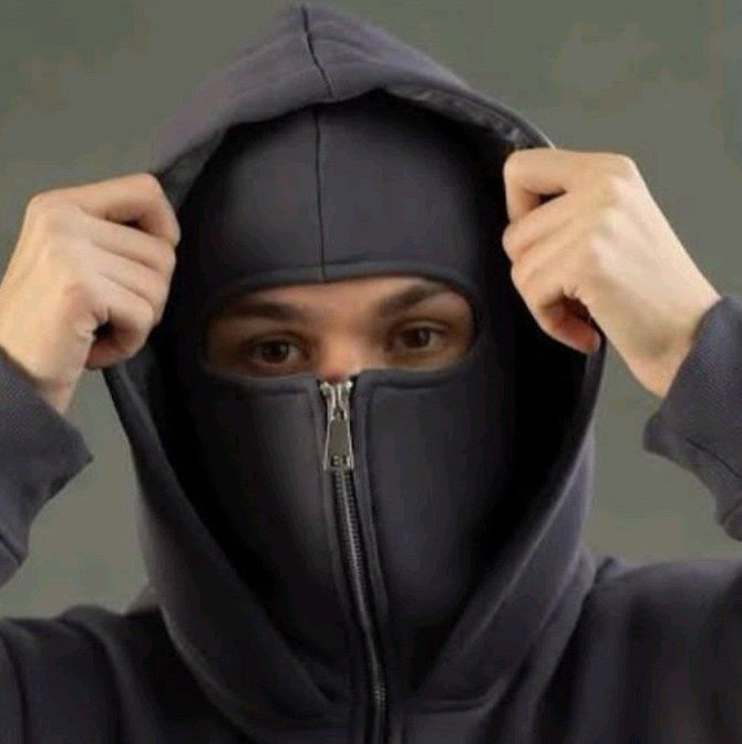 Person wearing a dark gray hoodie with a zipper, adjusting the hood against a neutral background.