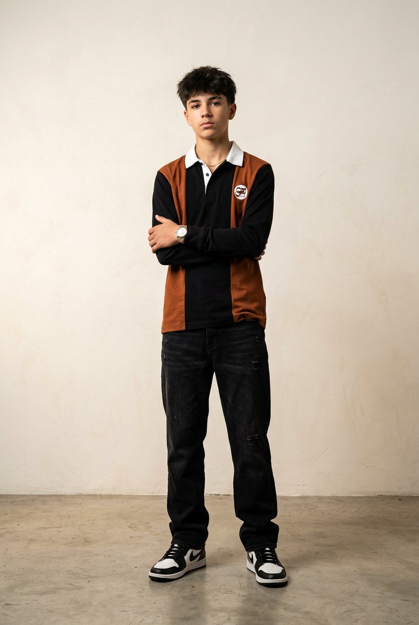 A long-sleeve rugby-style polo shirt with a color-blocked design featuring a rust brown body, black sleeves and center placket, and a white collar. A small circular logo is printed on the left chest.