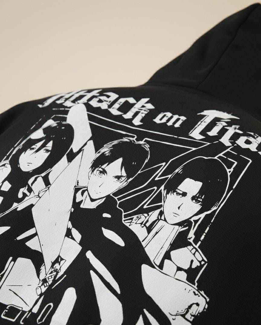 Black hoodie with 'Attack on Titan' character design on a beige background
