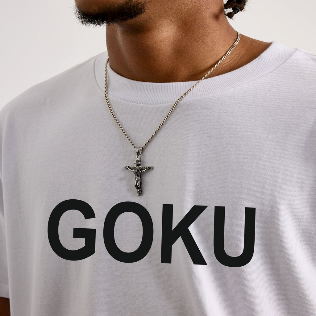 Person wearing a white t-shirt with 'GOKU' printed on it, necklaces visible.