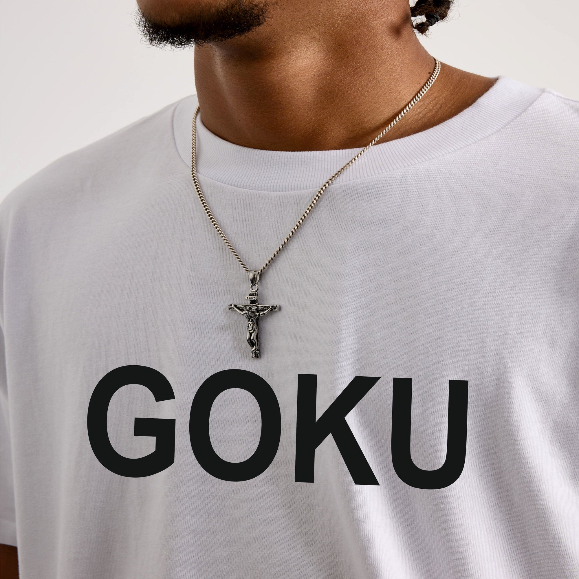 Person wearing a white t-shirt with 'GOKU' printed on it, necklaces visible.