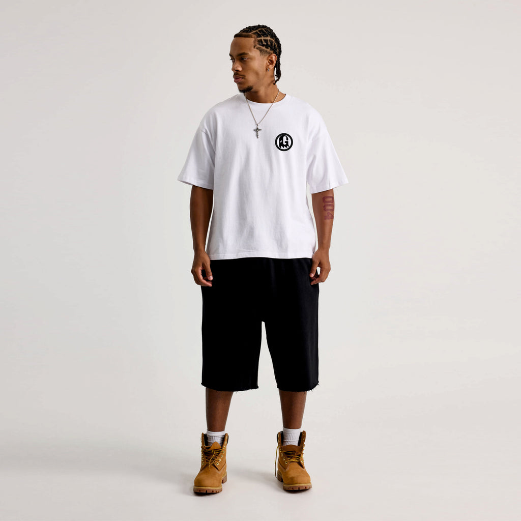 Person wearing a white t-shirt with a black logo, black shorts, and brown boots