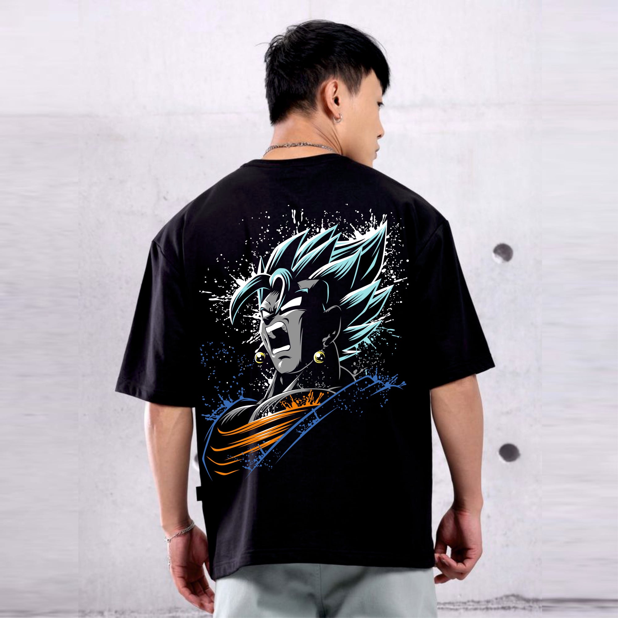 Person wearing a black t-shirt with a colorful graphic Goku design on the back, standing against a light gray wall.