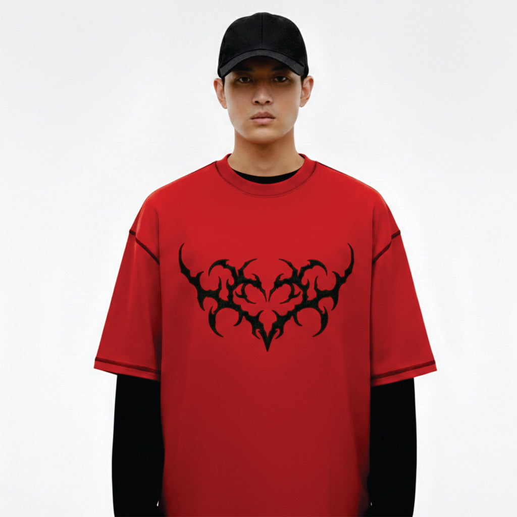 Person wearing a red t-shirt with black tribal design on a white background