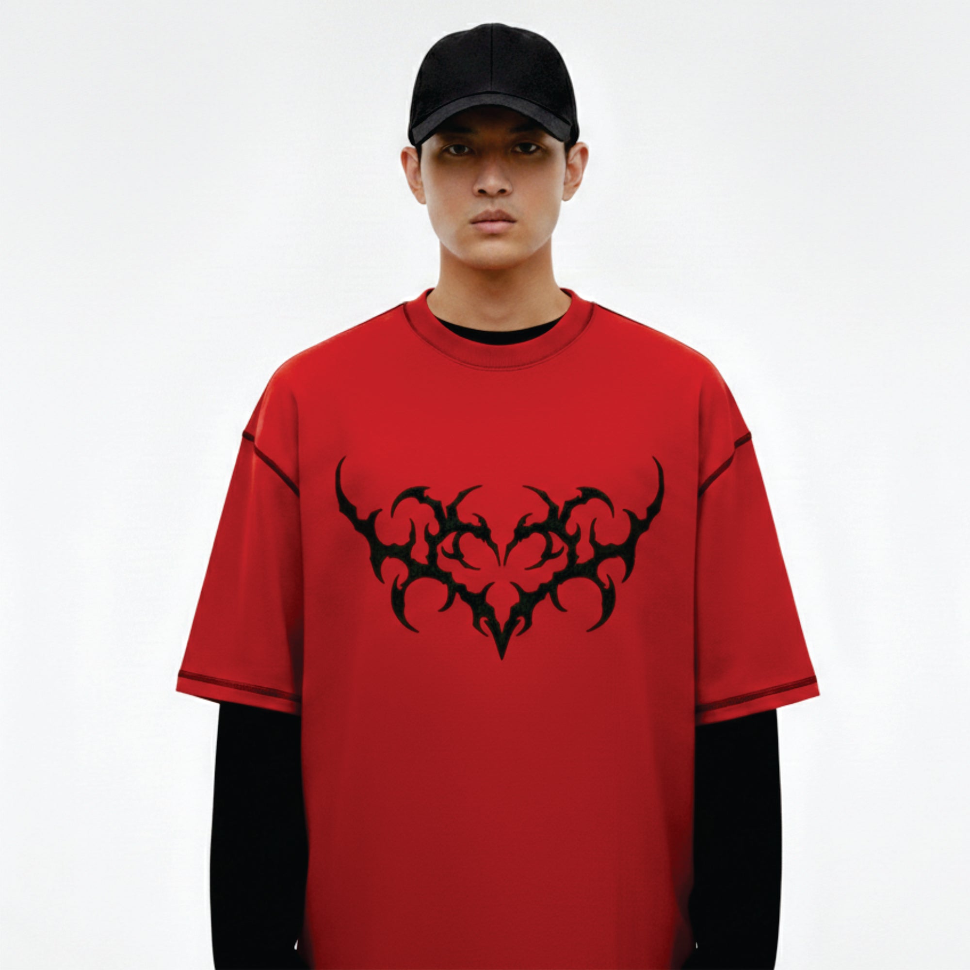 Person wearing a red t-shirt with black tribal design on a white background