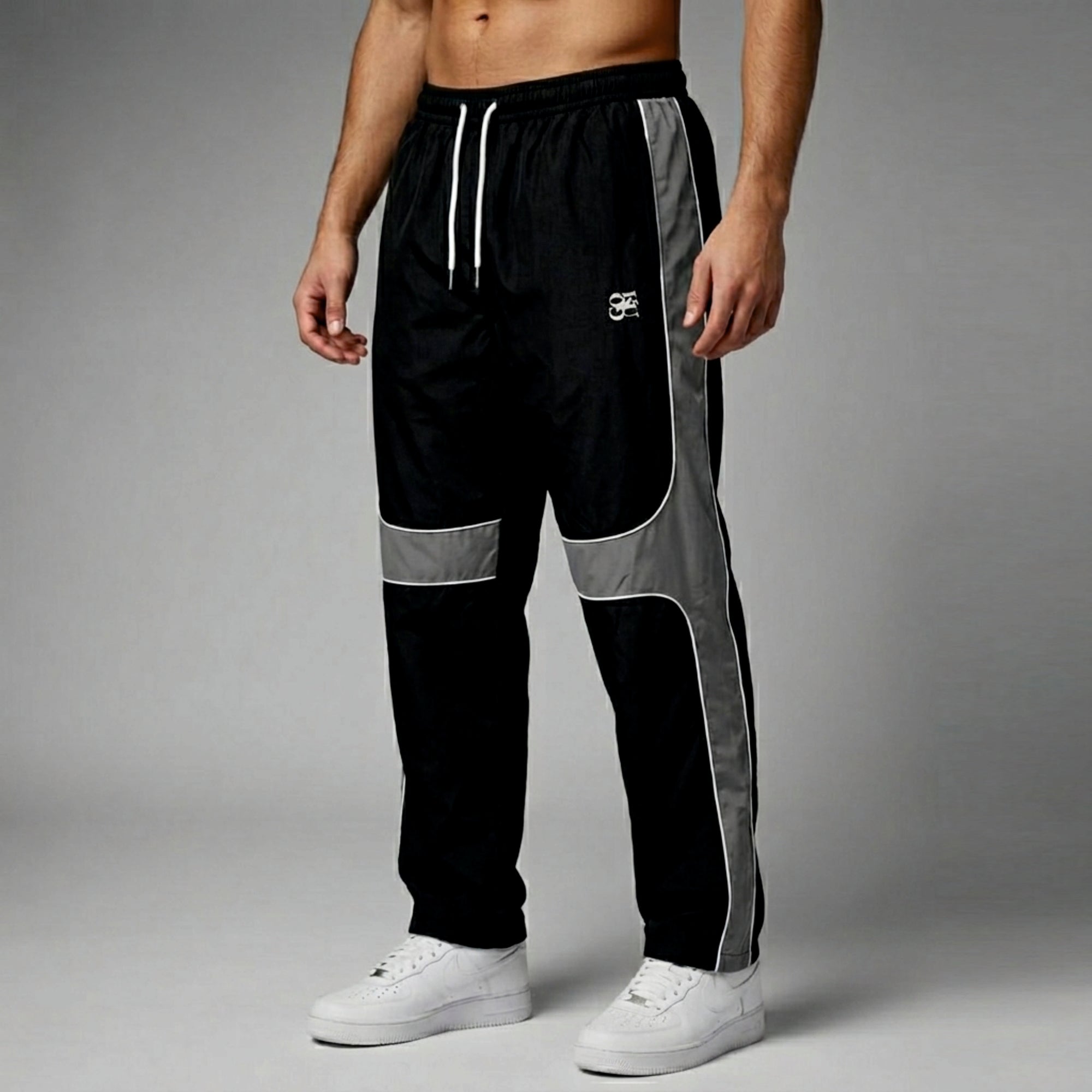 Black and gray track pants with white accents on a gray background