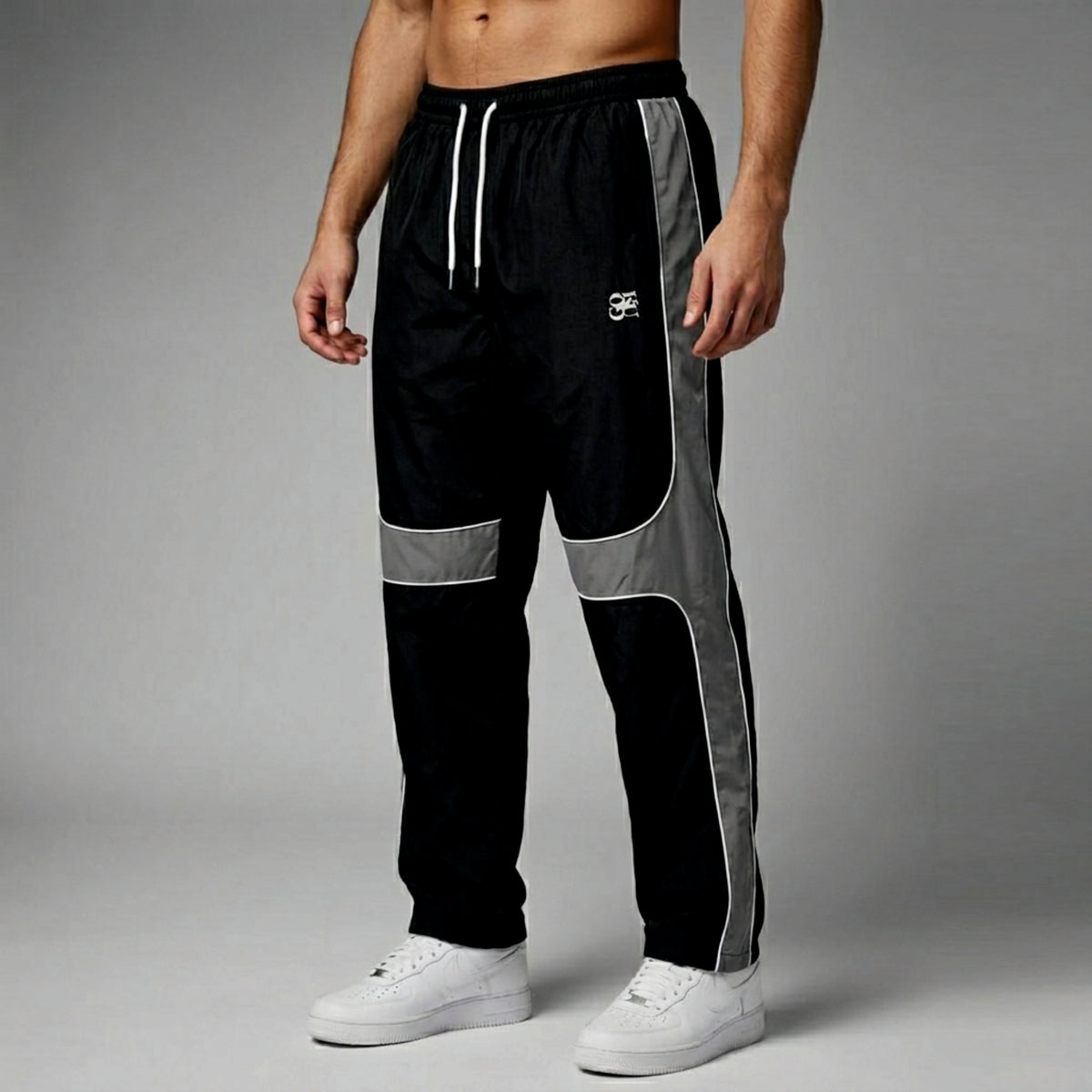 Black and gray track pants with white accents on a gray background