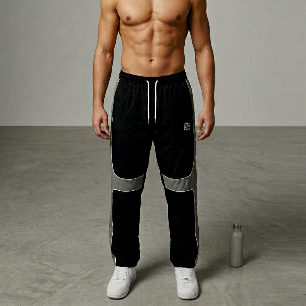 Man wearing black athletic pants with reflective stripes on a gray background