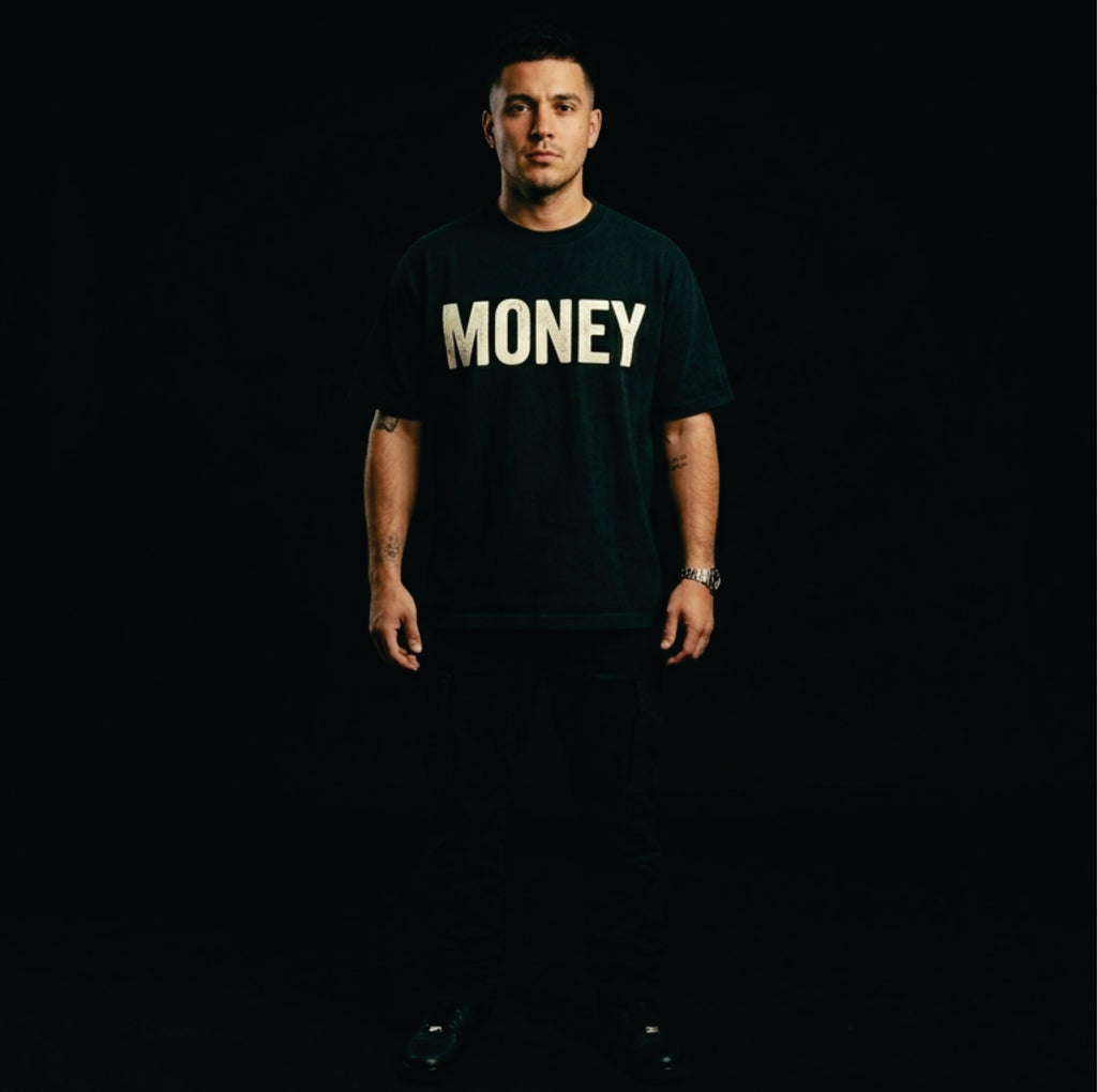 Person wearing a black t-shirt with 'MONEY' printed in white on a dark background