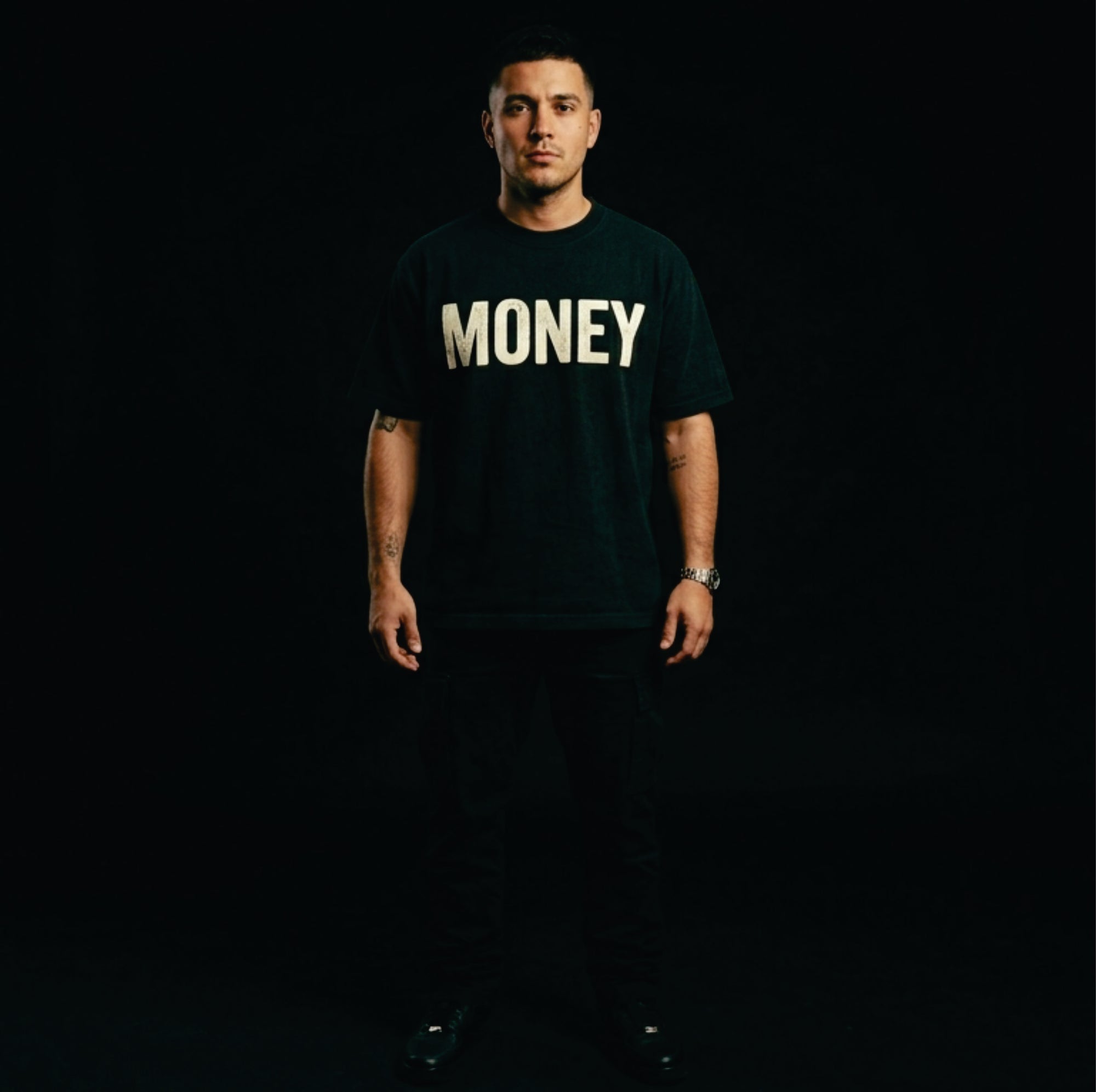 Person wearing a black t-shirt with 'MONEY' printed in white on a dark background