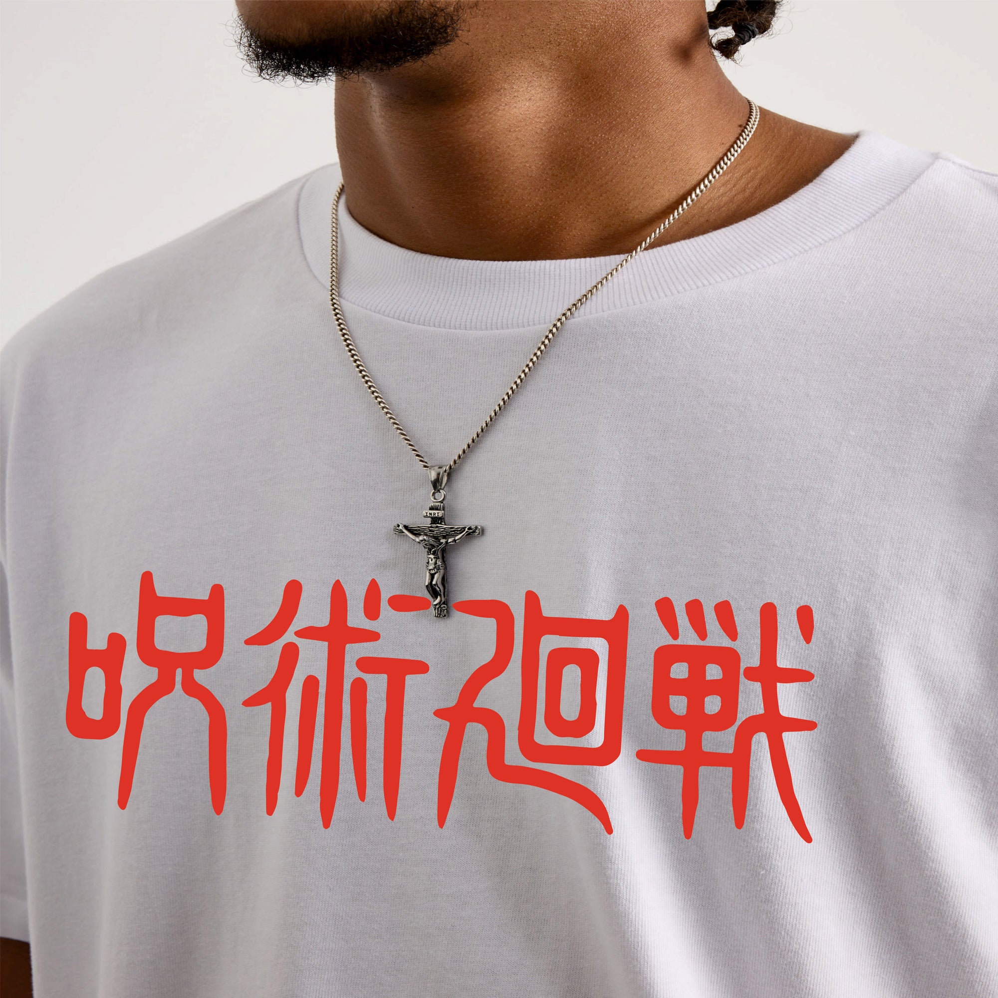 Person wearing a white t-shirt with red jujutsu Kaisen text and a necklace with a cross pendant.