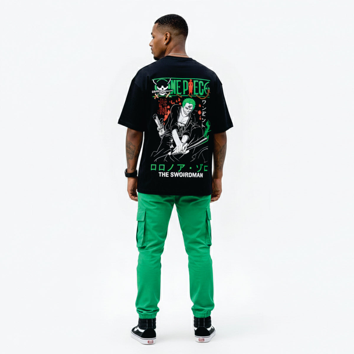 Person wearing a black t-shirt with graphic design and green pants on a white background