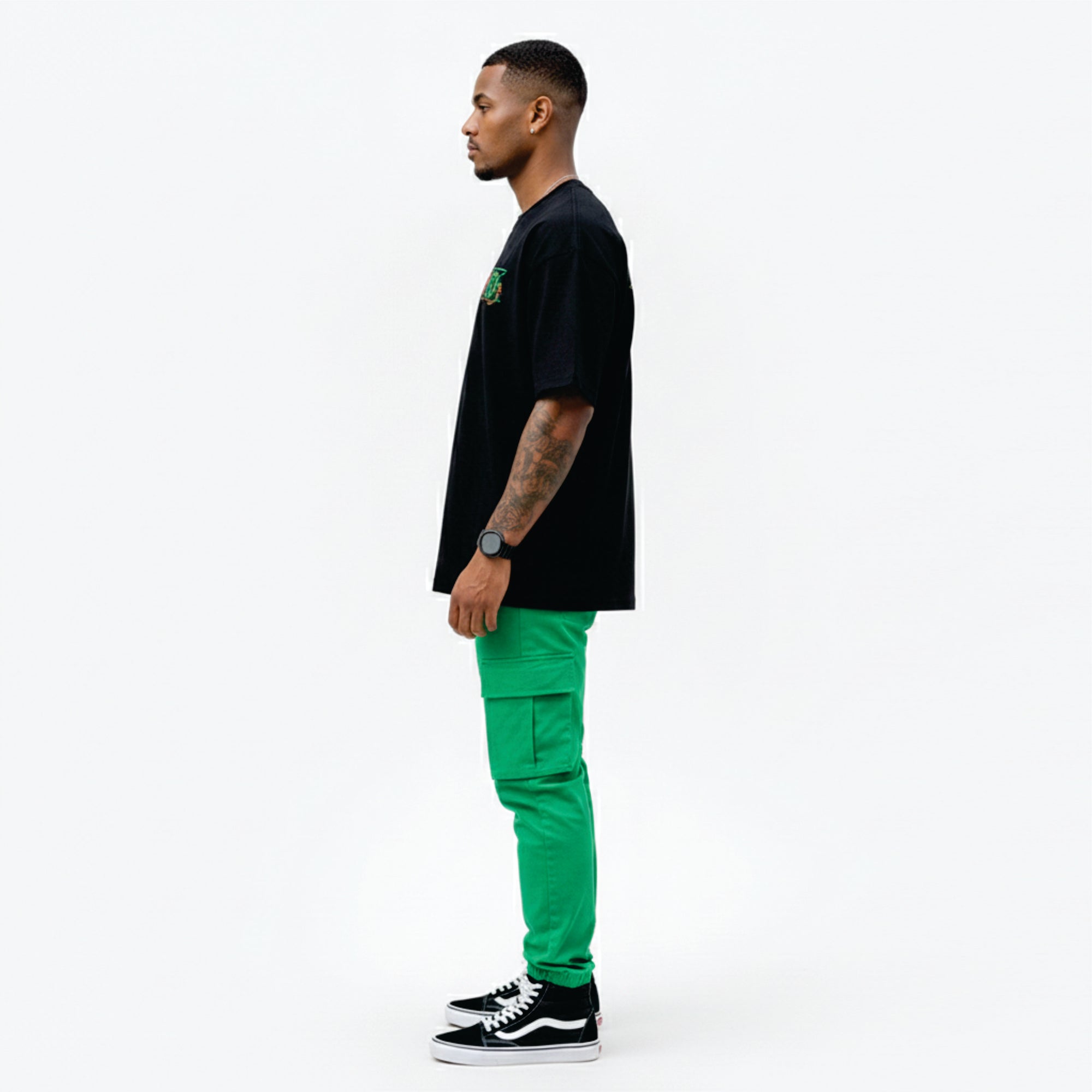 Man wearing a black t-shirt and bright green pants on a white background