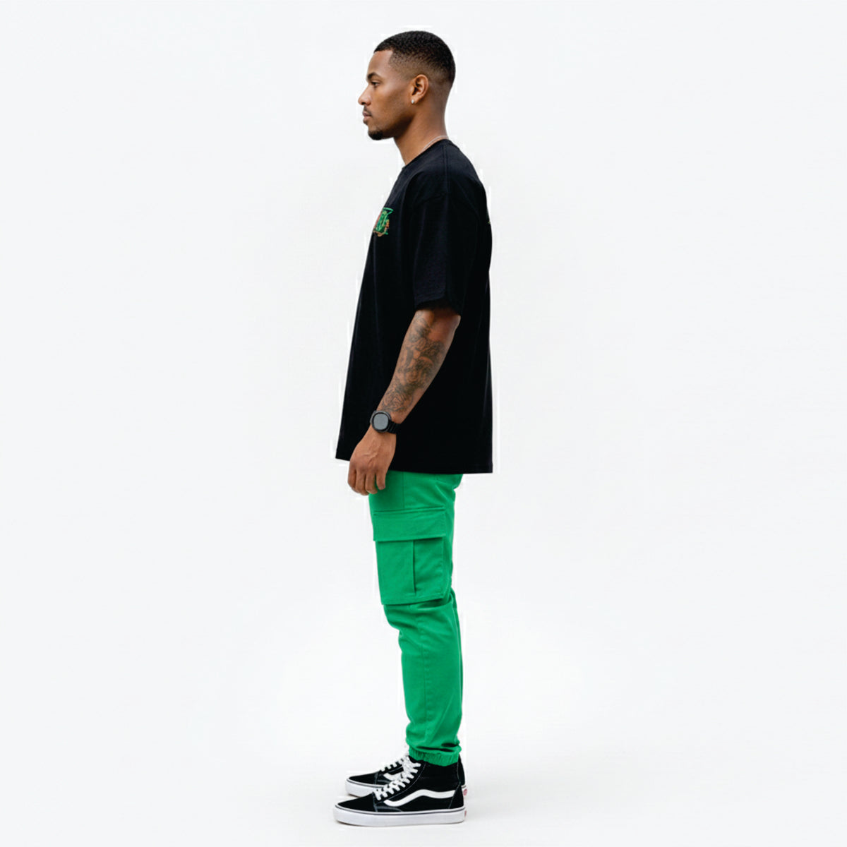 Man wearing a black t-shirt and bright green pants on a white background