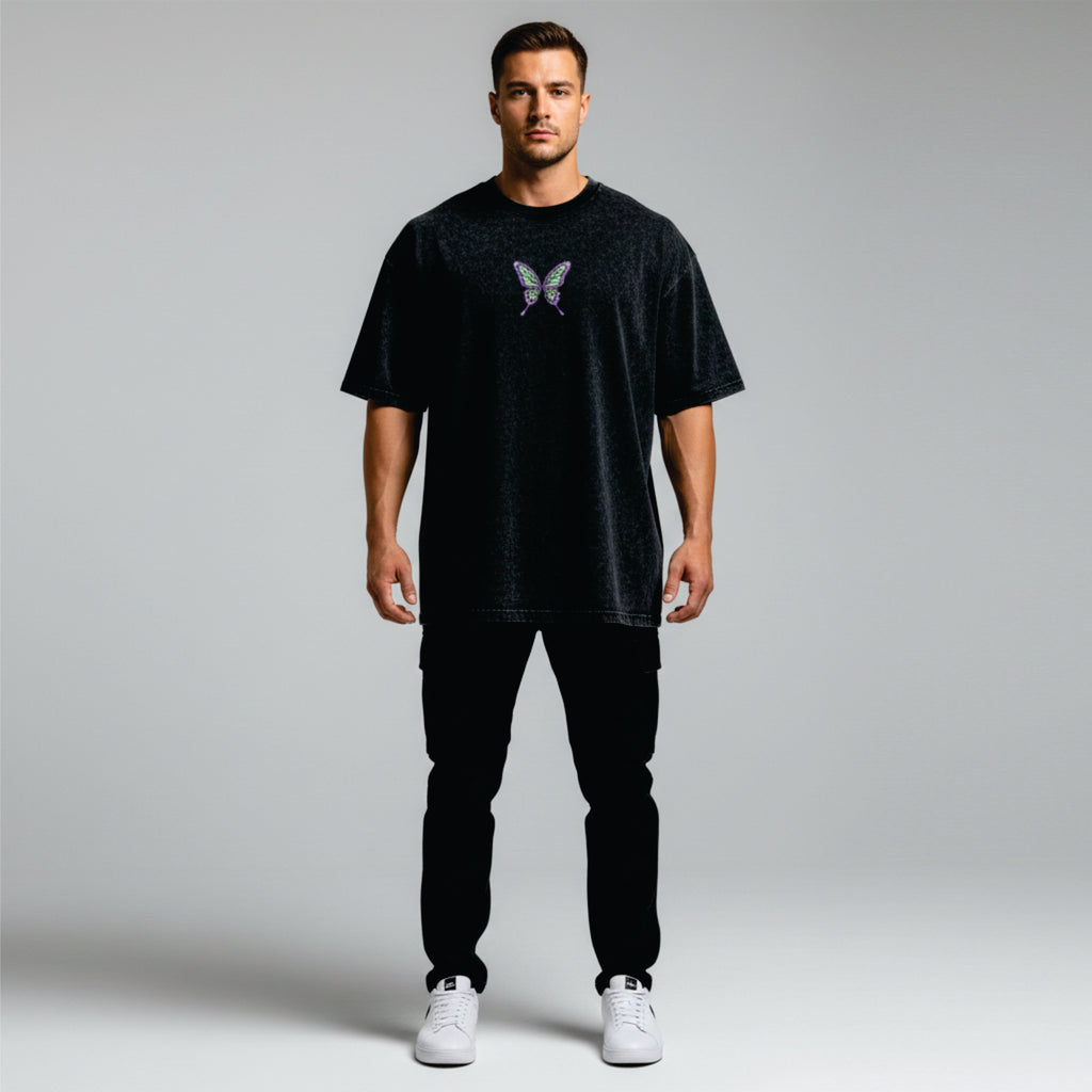 Man wearing a black t-shirt with a butterfly design on a plain background