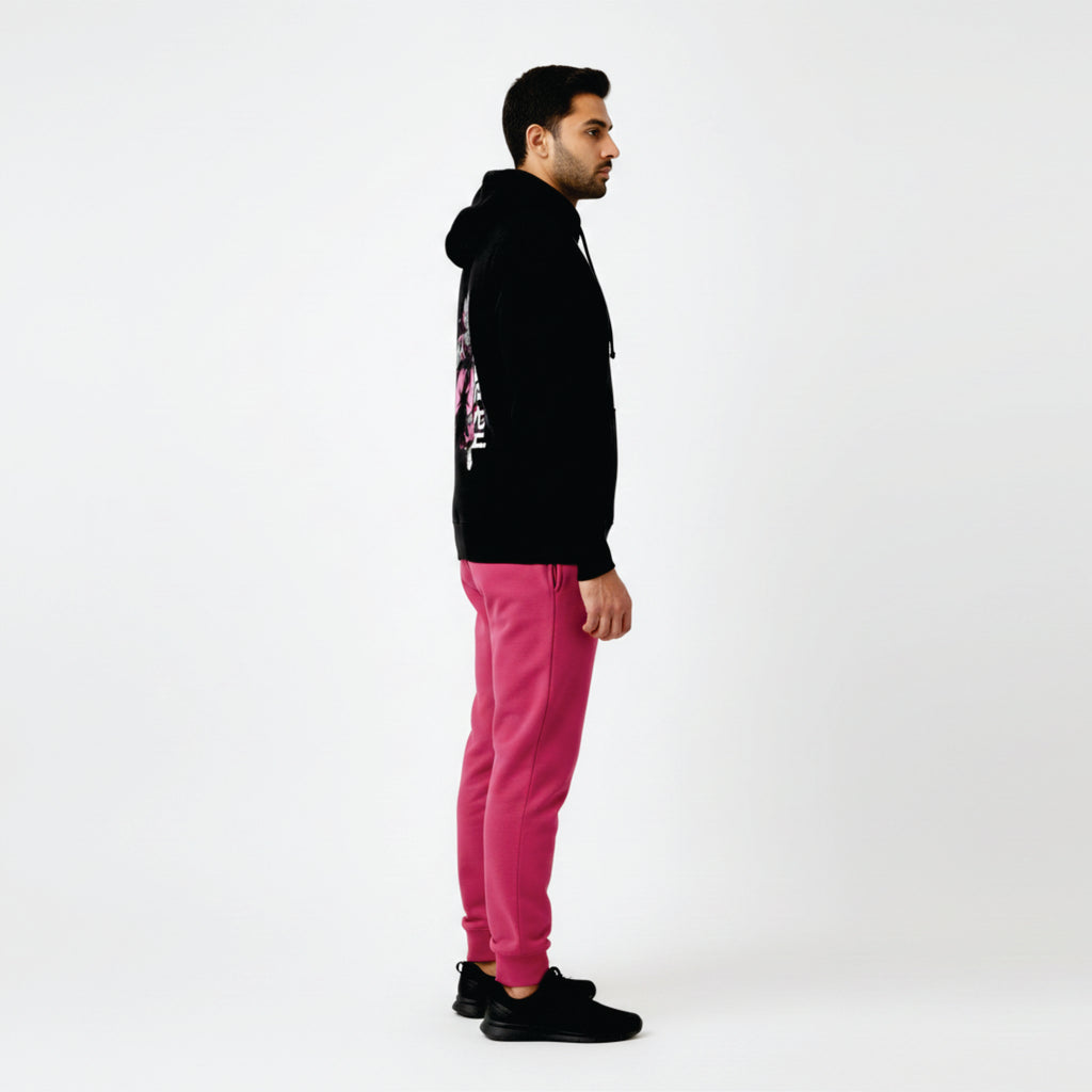 Person wearing a black hoodie and pink pants on a white background