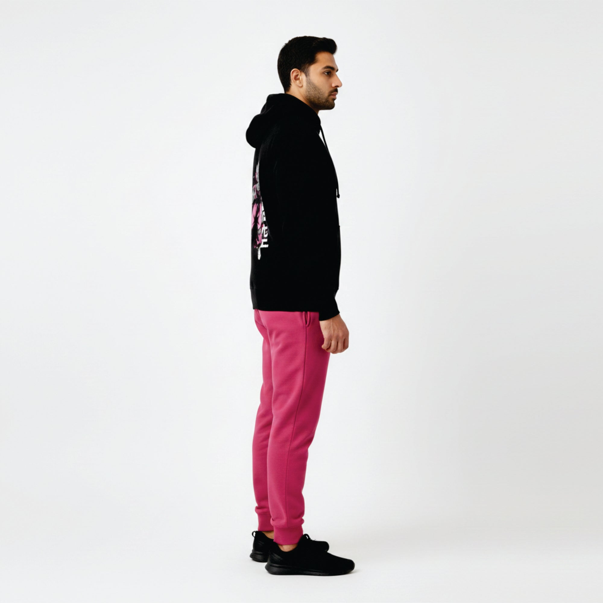 Person wearing a black hoodie and pink pants on a white background