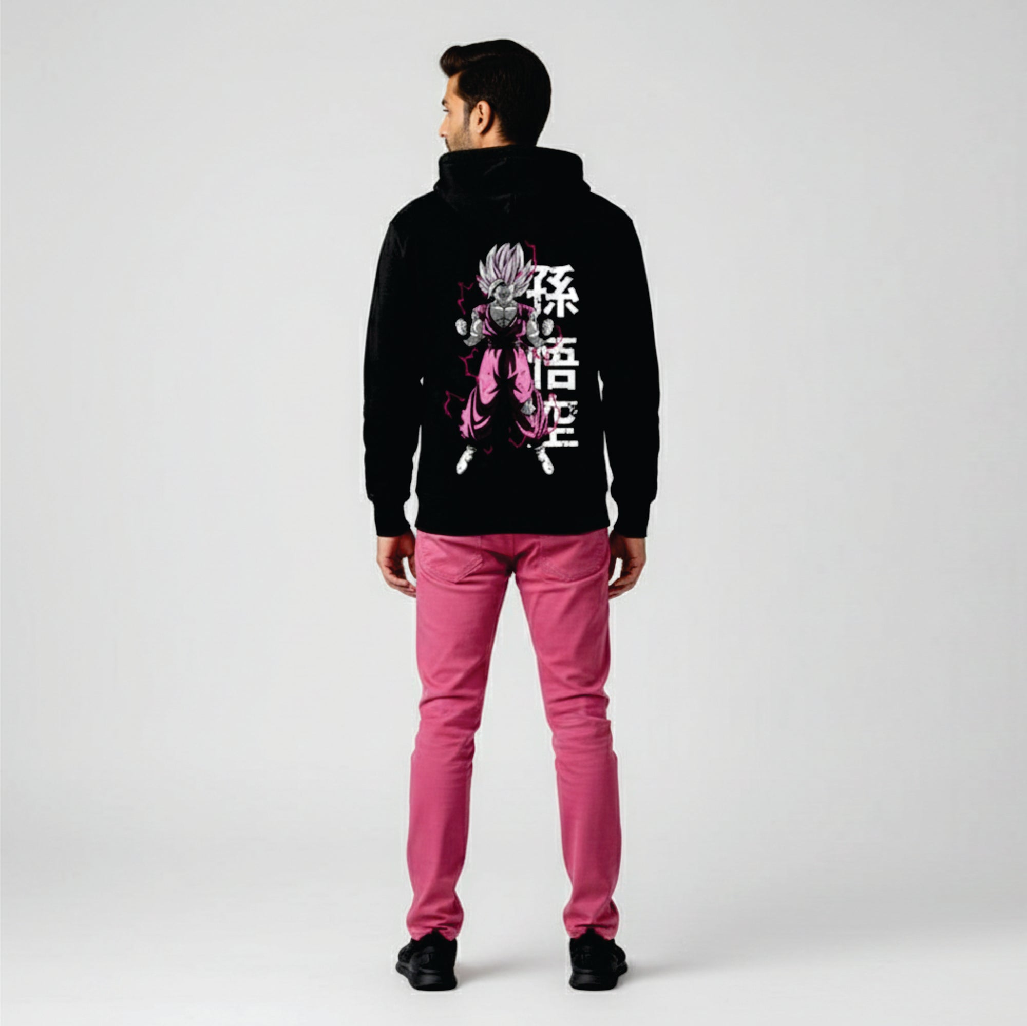Person wearing a black hoodie with a graphic design and pink pants on a white background