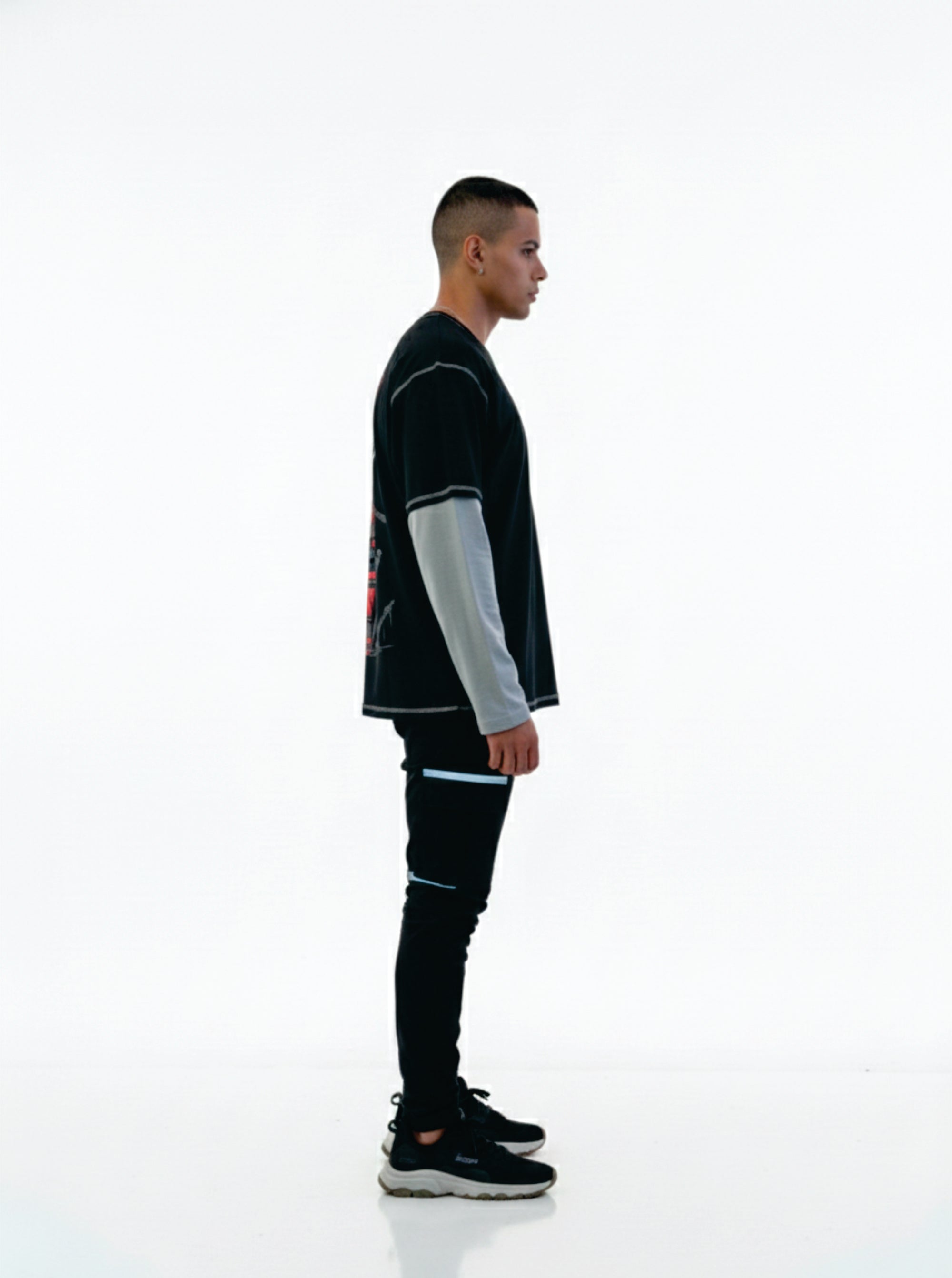 Person wearing a black outfit with reflective elements on a white background
