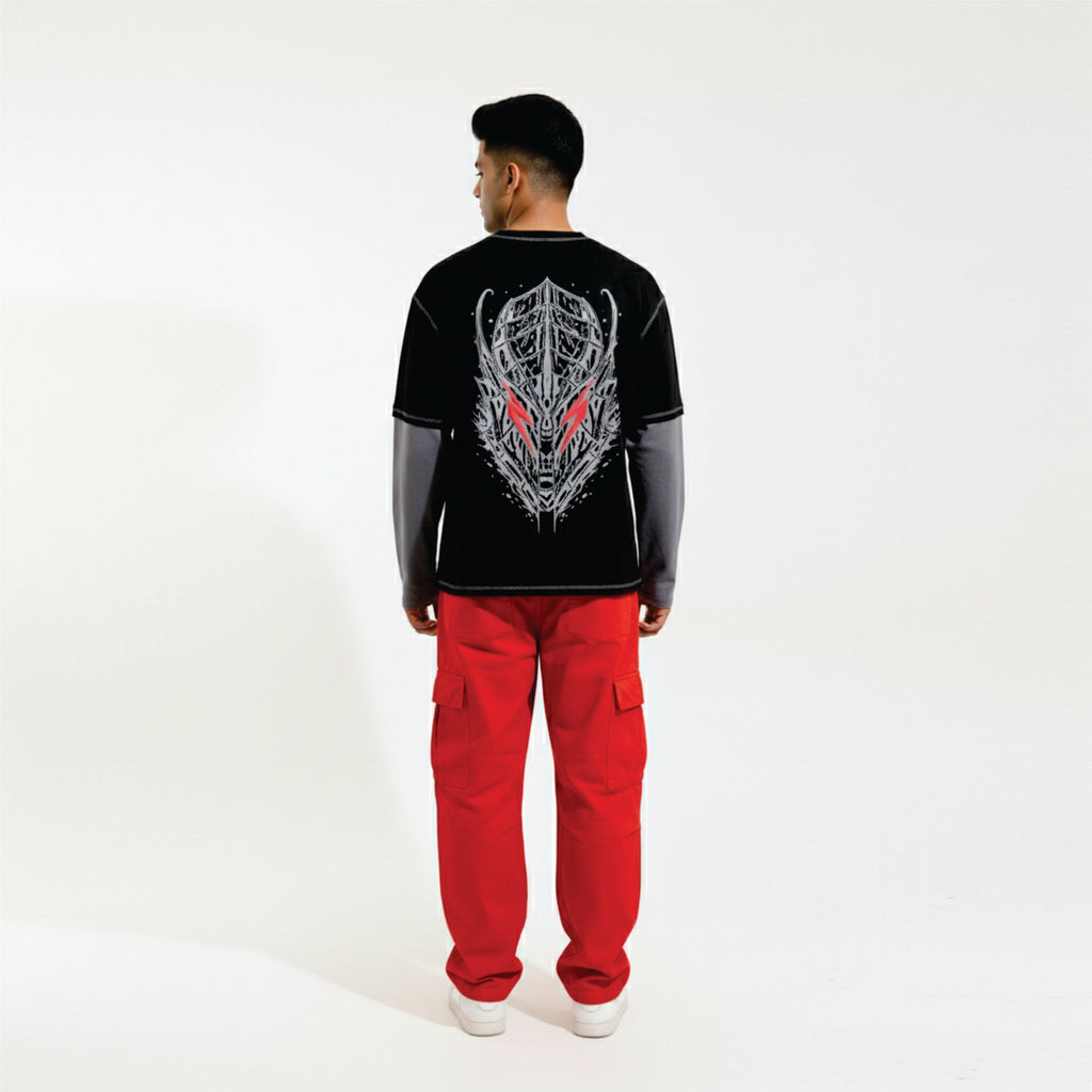 Person wearing a black long-sleeve shirt with a graphic design and red pants on a white background