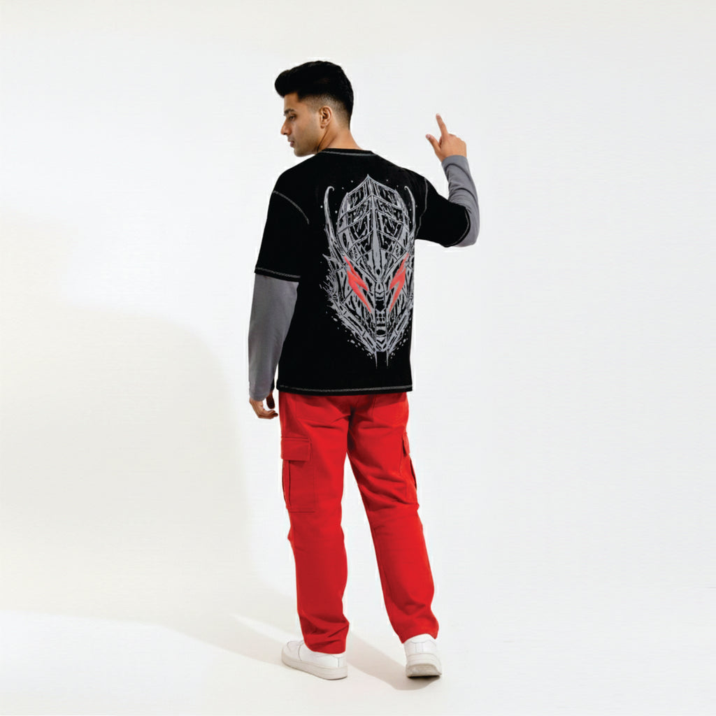 Person wearing a black long-sleeve shirt with a graphic design and red pants on a white background