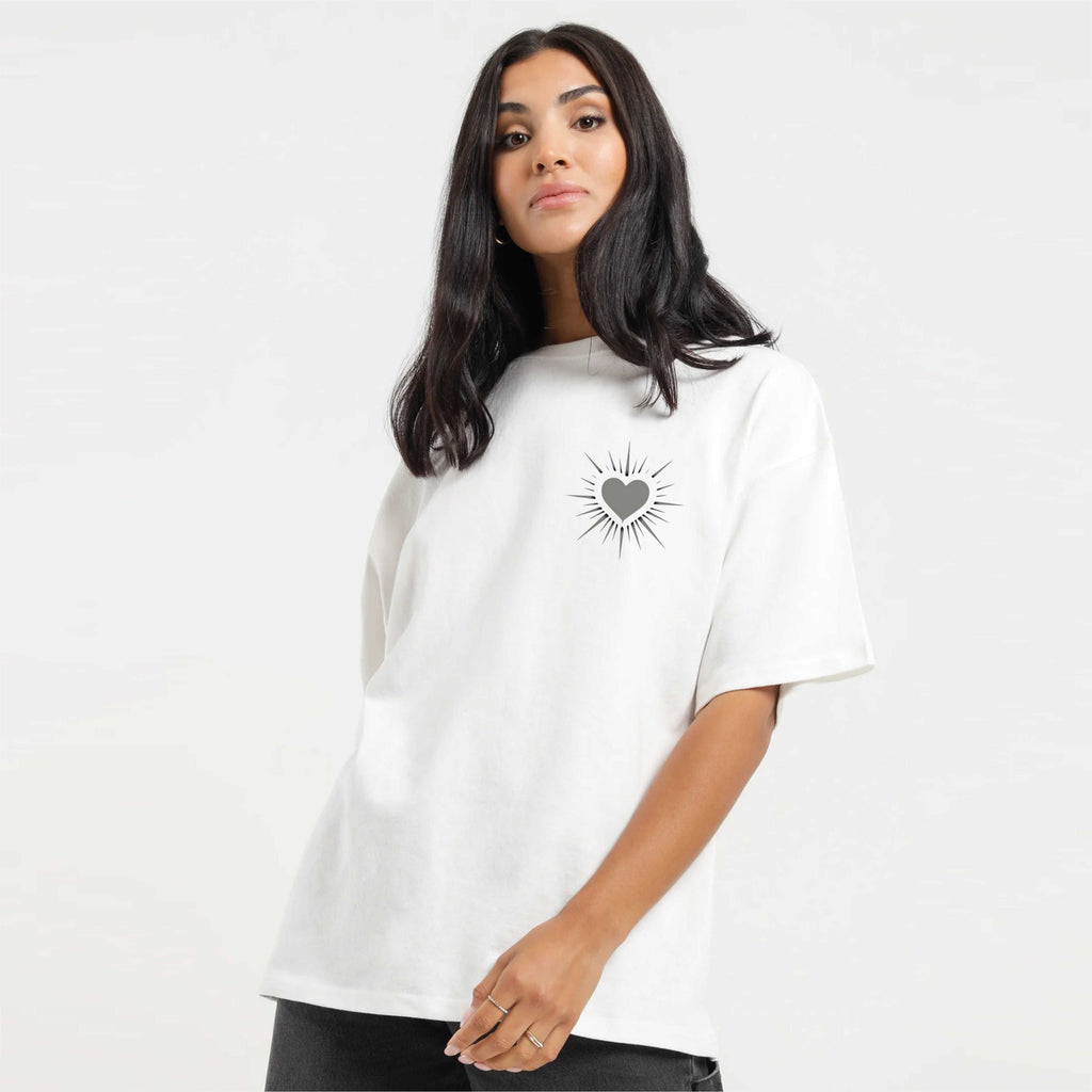 Woman wearing a white t-shirt with a black heart design on a plain background