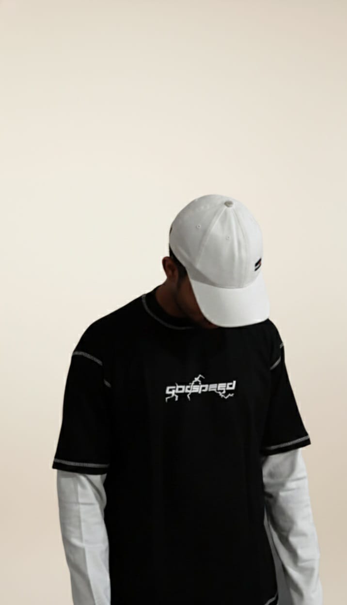 Person wearing a black t-shirt with a logo and a white cap on a beige background